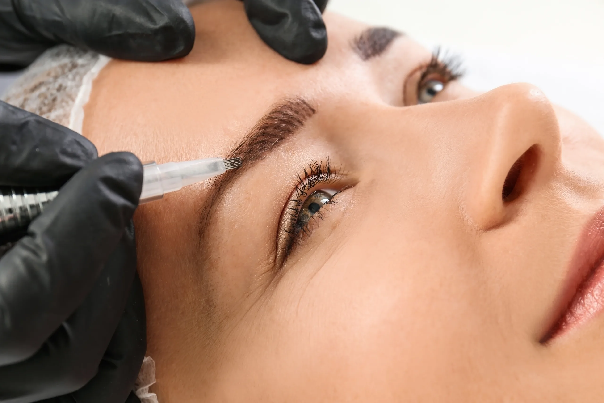 Woman receiving an eyebrow microblading treatment